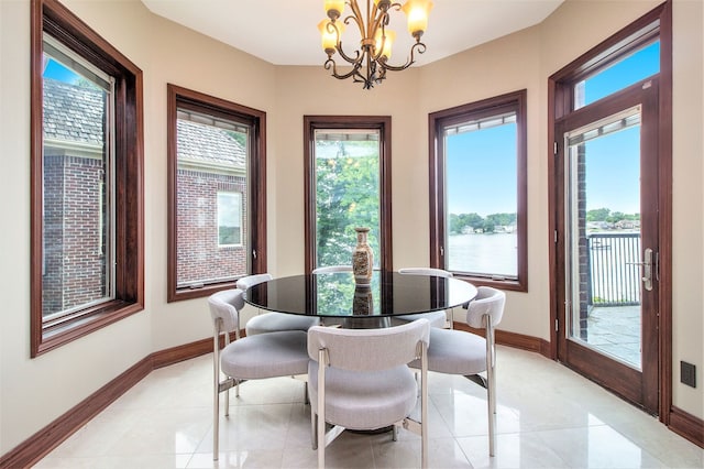 tiled dining area with a notable chandelier, a water view, and a wealth of natural light