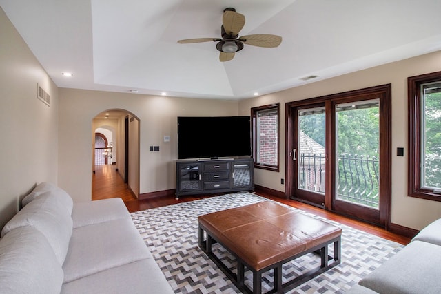 living room featuring a raised ceiling, ceiling fan, and wood-type flooring