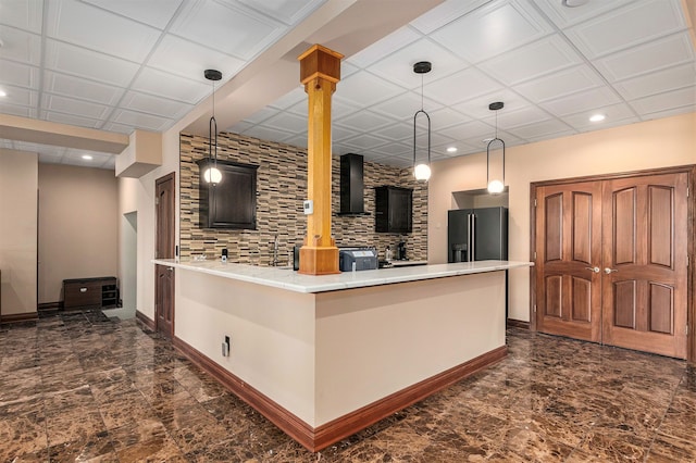 kitchen with wall chimney range hood, stainless steel fridge with ice dispenser, kitchen peninsula, pendant lighting, and a breakfast bar