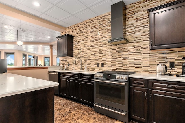 kitchen featuring stainless steel range oven, wall chimney range hood, backsplash, and hanging light fixtures