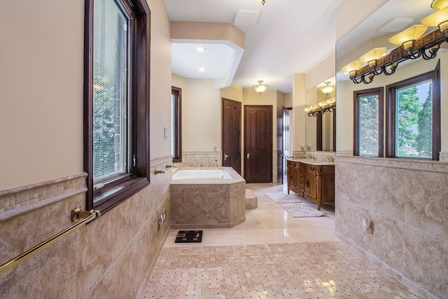 bathroom with vanity, tile walls, and tiled bath