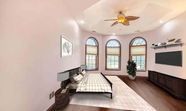 bedroom with ceiling fan, dark wood-type flooring, and a tray ceiling