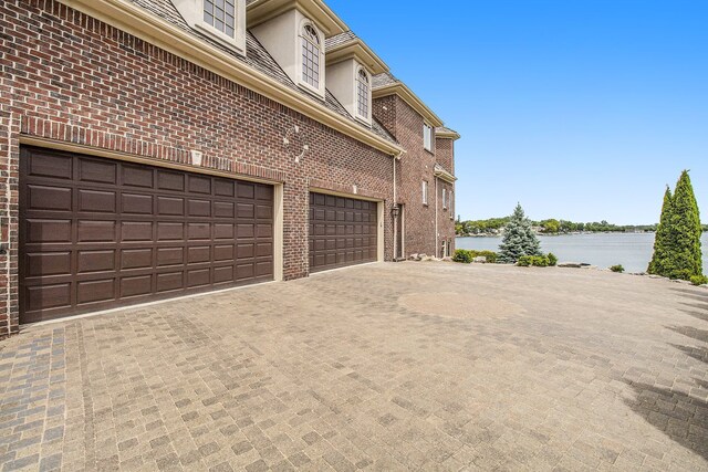 75 Chateaux Du Lac, Fenton, MI 48430 - garage featuring a water view and decorative driveway
