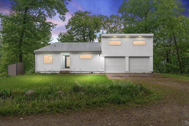 back house at dusk with a yard and a garage