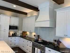 kitchen featuring stainless steel appliances, premium range hood, white cabinetry, backsplash, and beam ceiling