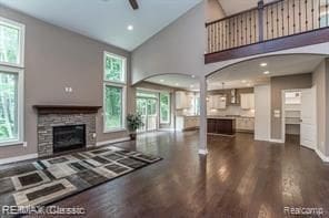 unfurnished living room featuring a fireplace, dark wood-type flooring, high vaulted ceiling, and a healthy amount of sunlight