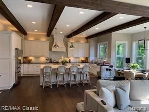 kitchen with white cabinetry, hanging light fixtures, beam ceiling, and a breakfast bar