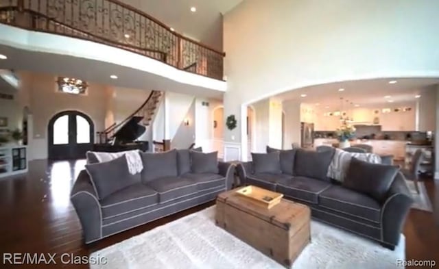 living room featuring french doors, a towering ceiling, and wood-type flooring