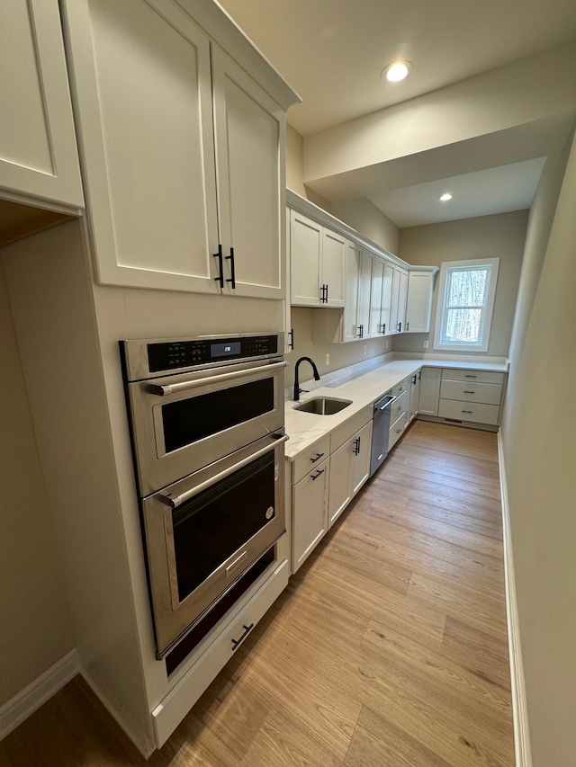 kitchen with stainless steel appliances, light hardwood / wood-style floors, sink, and white cabinets