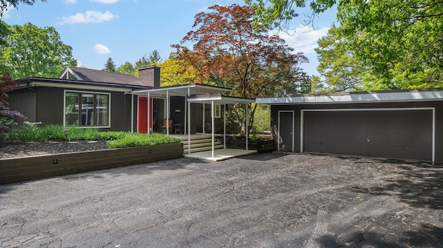 view of front of home with a carport, a garage, and an outbuilding