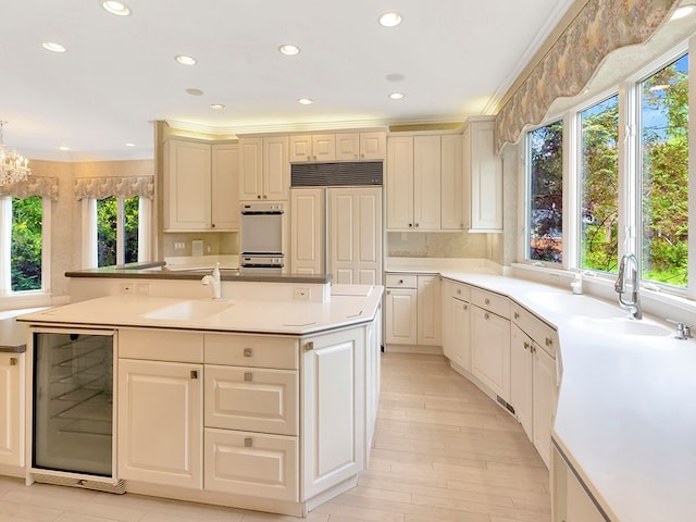 kitchen with wine cooler, sink, a healthy amount of sunlight, and paneled fridge