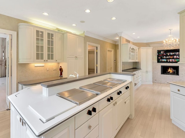 kitchen featuring an inviting chandelier, crown molding, a fireplace, decorative light fixtures, and a kitchen island