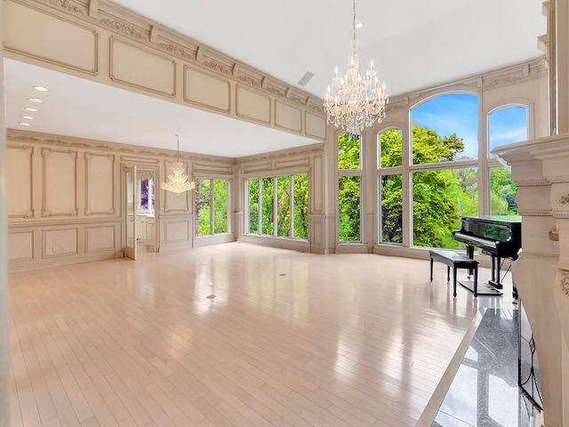 miscellaneous room with a high ceiling, light hardwood / wood-style floors, and an inviting chandelier