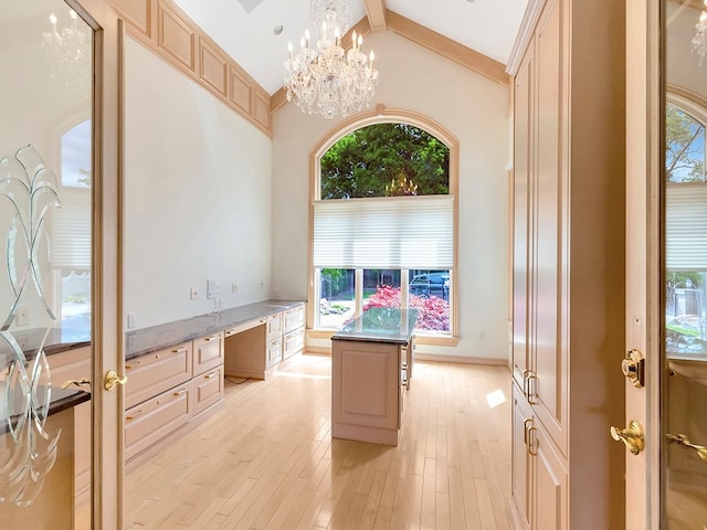 home office with beamed ceiling, a notable chandelier, a healthy amount of sunlight, and light hardwood / wood-style floors