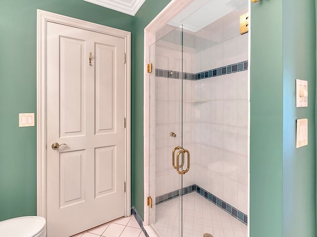 bathroom with tile patterned floors, toilet, a shower with shower door, and ornamental molding