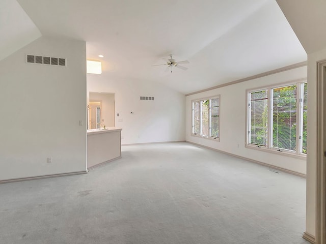 unfurnished living room with ceiling fan, light colored carpet, vaulted ceiling, and ornamental molding