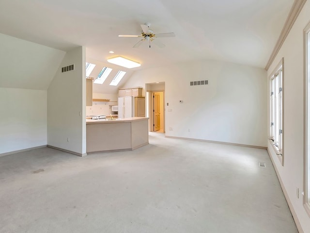 unfurnished living room with vaulted ceiling with skylight and ceiling fan