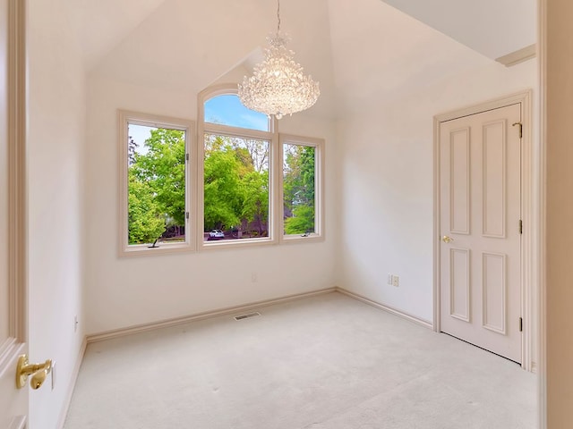 carpeted spare room with a notable chandelier, plenty of natural light, and vaulted ceiling