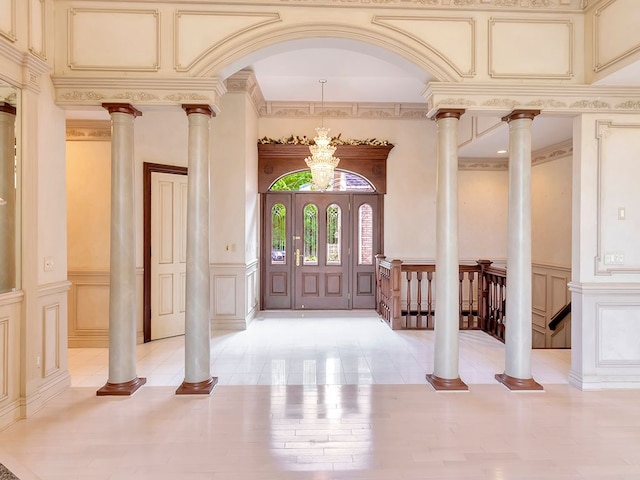 foyer entrance with ornate columns, ornamental molding, and an inviting chandelier