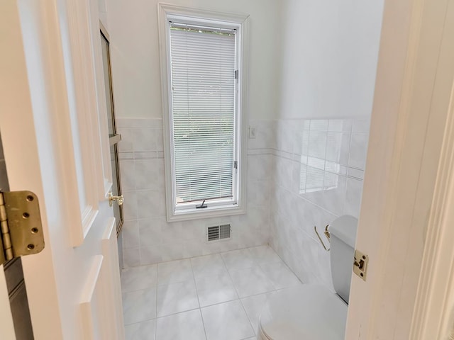 bathroom with tile patterned floors, toilet, and tile walls