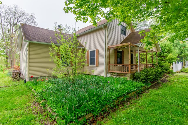 rear view of property featuring covered porch and a yard