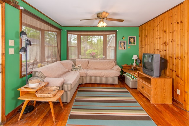 living room with wooden walls, hardwood / wood-style floors, and ceiling fan