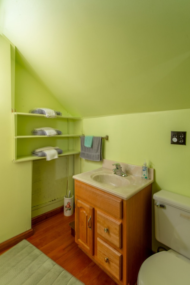 bathroom featuring hardwood / wood-style floors, vanity, toilet, and lofted ceiling