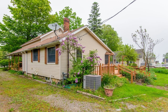 view of side of home with a lawn, central AC, and a wooden deck