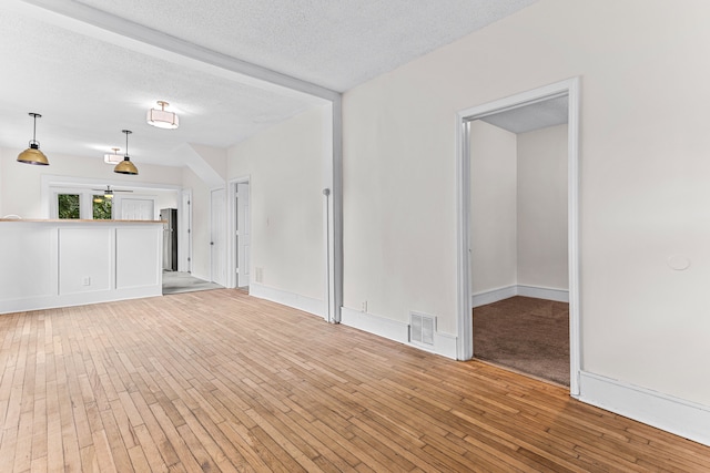 unfurnished living room with a textured ceiling and light wood-type flooring