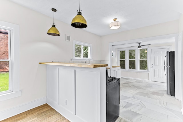 kitchen featuring kitchen peninsula, stainless steel fridge, a textured ceiling, black range, and light hardwood / wood-style floors