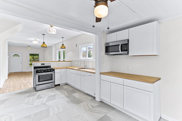 kitchen featuring a wealth of natural light, white cabinetry, hanging light fixtures, and stainless steel appliances