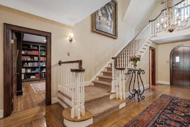 staircase with built in shelves, hardwood / wood-style floors, vaulted ceiling, and an inviting chandelier