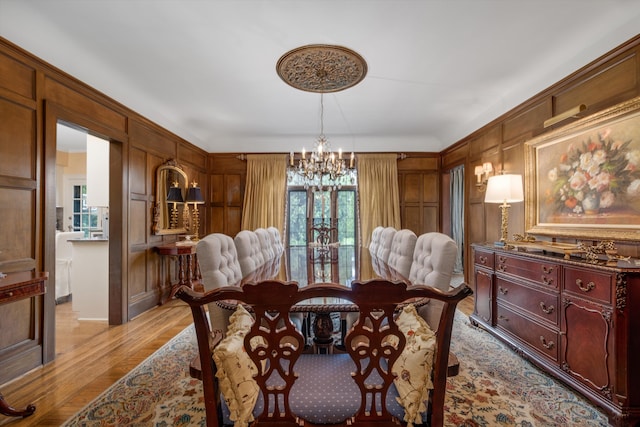 dining area featuring a chandelier, light hardwood / wood-style flooring, a wealth of natural light, and wood walls