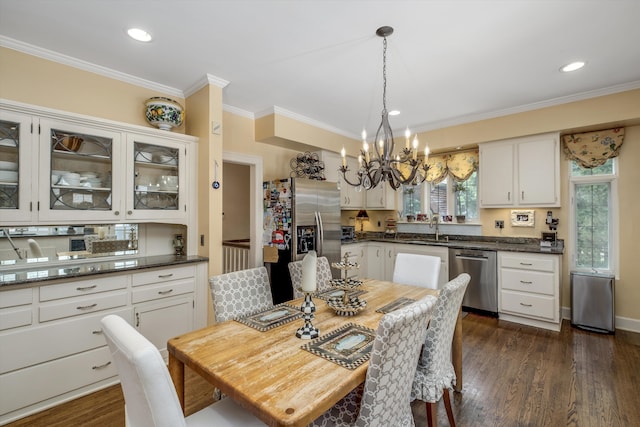 dining room with sink, crown molding, dark wood-type flooring, and an inviting chandelier