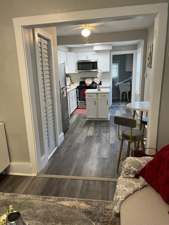 kitchen featuring white cabinetry, dark hardwood / wood-style flooring, ceiling fan, and appliances with stainless steel finishes