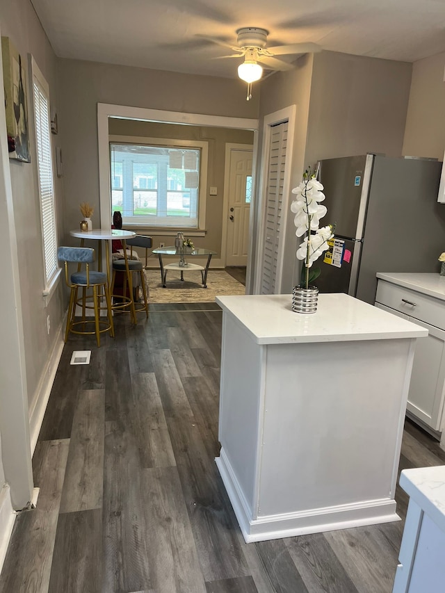 kitchen featuring stainless steel refrigerator, white cabinetry, dark hardwood / wood-style flooring, and ceiling fan