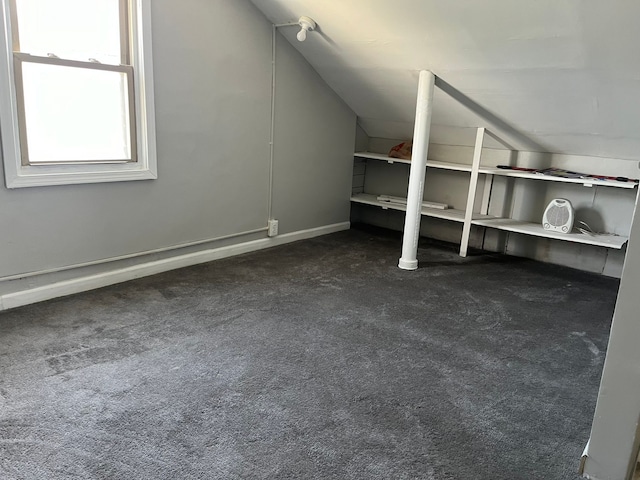 bonus room with dark colored carpet and lofted ceiling