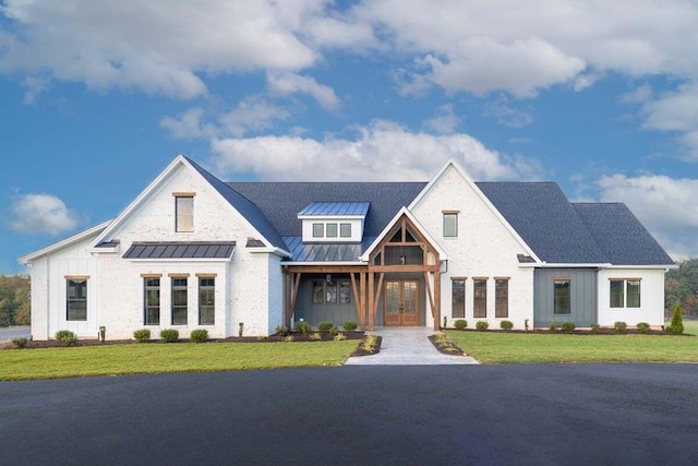 modern inspired farmhouse with metal roof, a standing seam roof, a front yard, and board and batten siding