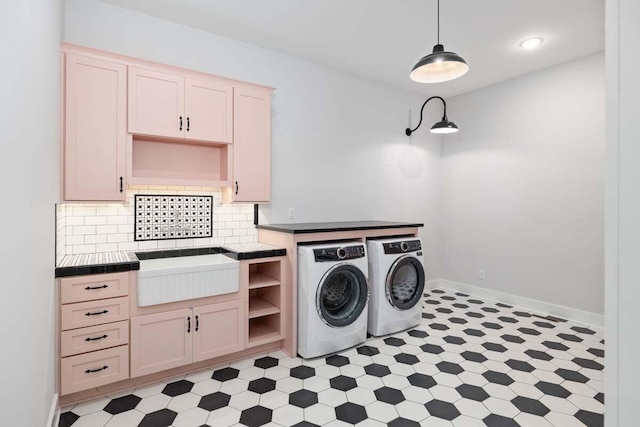 washroom with light floors, washing machine and dryer, cabinet space, and baseboards