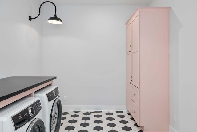 clothes washing area featuring cabinet space, washing machine and dryer, baseboards, and light floors