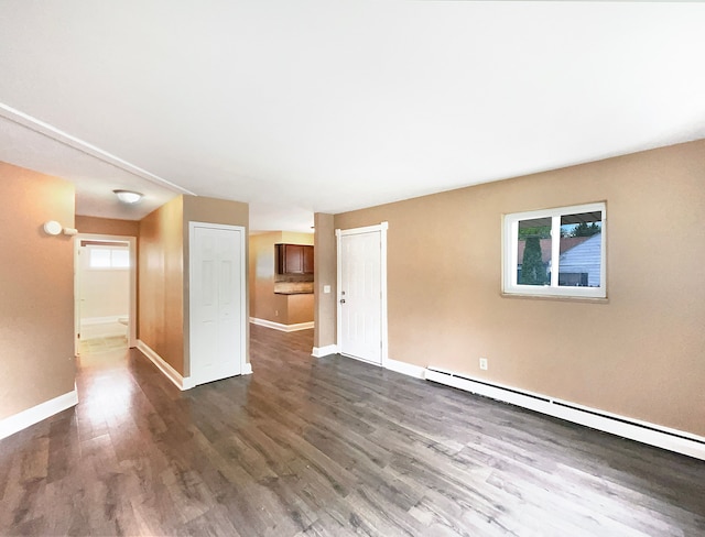 empty room featuring baseboard heating and dark wood-type flooring