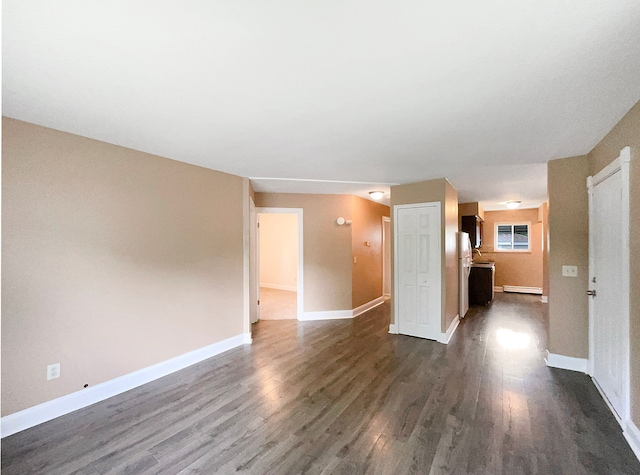 unfurnished living room featuring dark hardwood / wood-style flooring and a baseboard heating unit