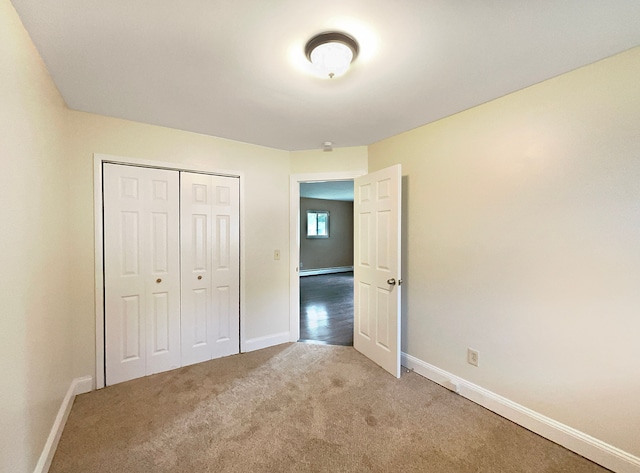 unfurnished bedroom featuring carpet, a baseboard radiator, and a closet