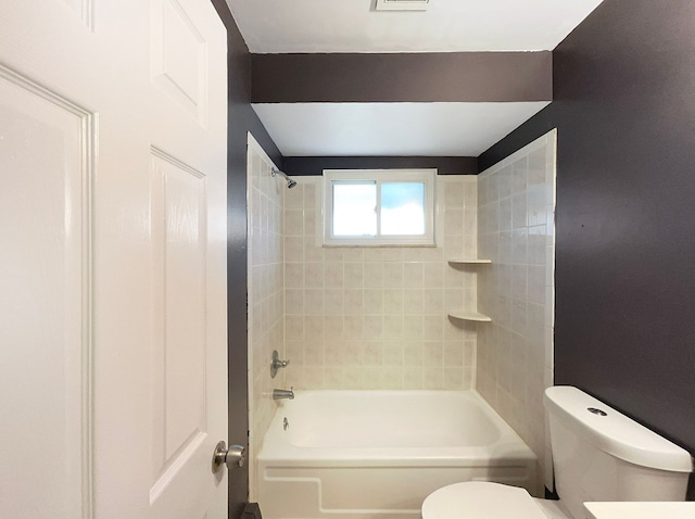 bathroom with toilet and tiled shower / bath