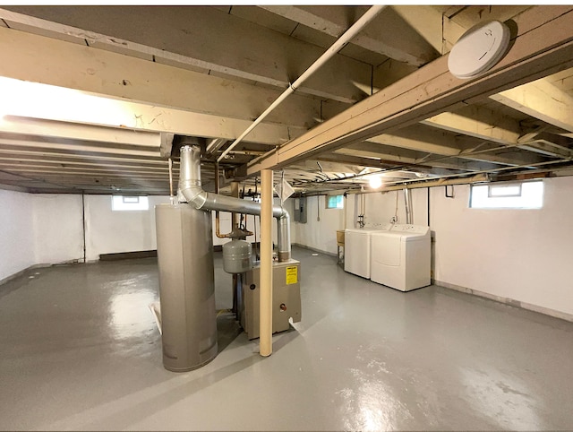 basement featuring washer and dryer, a healthy amount of sunlight, electric panel, and water heater