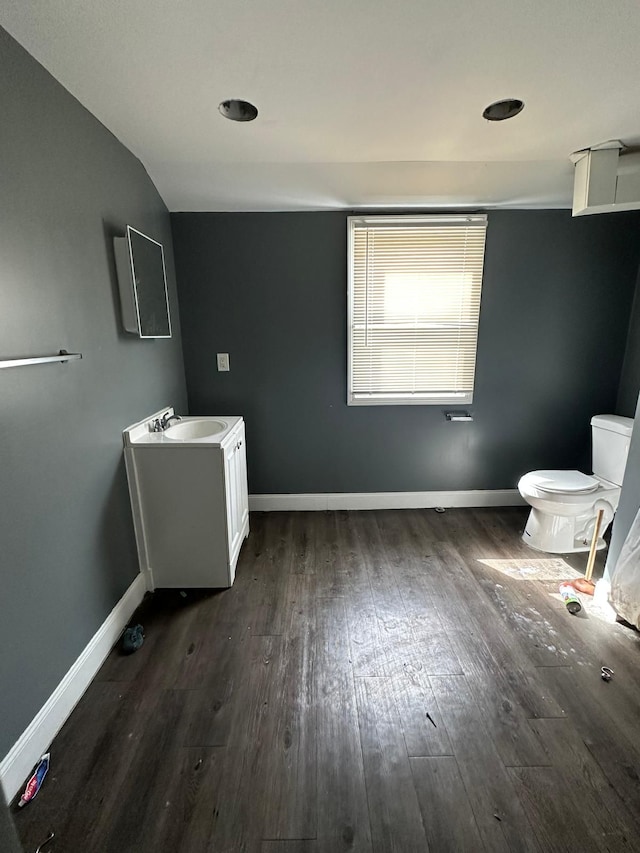 bathroom featuring vanity, toilet, wood-type flooring, and lofted ceiling