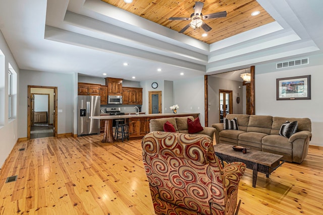 living room featuring ceiling fan, sink, wooden ceiling, light hardwood / wood-style floors, and a tray ceiling