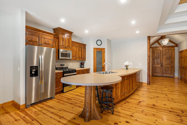 kitchen with a kitchen bar, sink, light hardwood / wood-style flooring, and appliances with stainless steel finishes