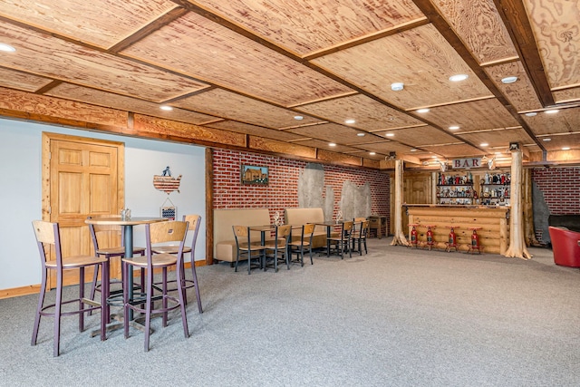 dining space with brick wall, carpet floors, bar, and wood ceiling