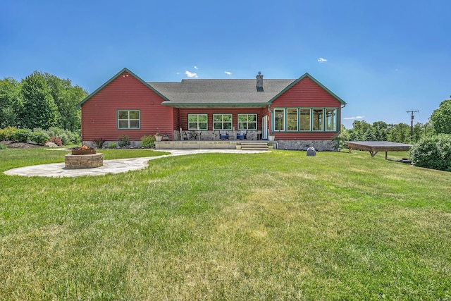 back of house featuring a sunroom, a fire pit, and a yard